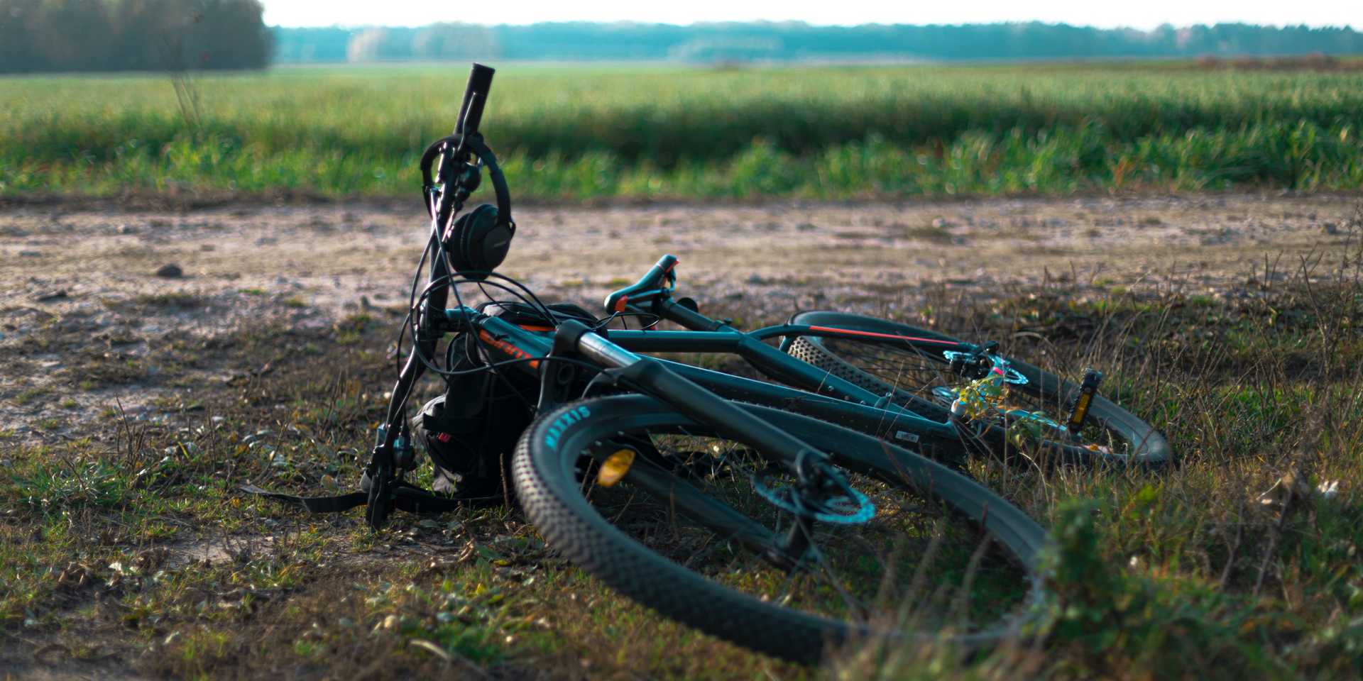 En mountainbike nedlagd på grusväg med åker i fonden